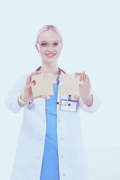 Woman doctor holding two connecting puzzle pieces — Stock Photo, Image