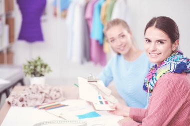 Güzel moda tasarımcısı stüdyoda masada oturuyor.