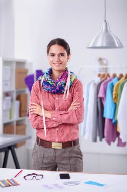 Güzel moda tasarımcısı stüdyoda masada oturuyor.