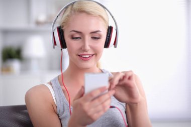 Evdeki genç ve güzel kadın kanepede oturup müzik dinliyor.