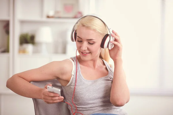 Joven hermosa mujer en casa sentada en el sofá y escuchando música —  Fotos de Stock