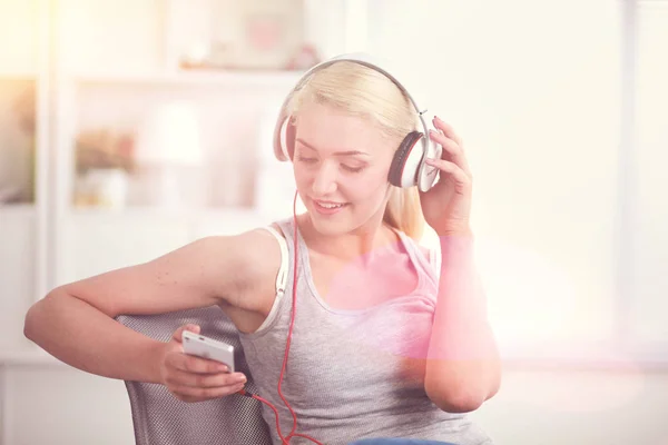 Joven hermosa mujer en casa sentada en el sofá y escuchando música —  Fotos de Stock