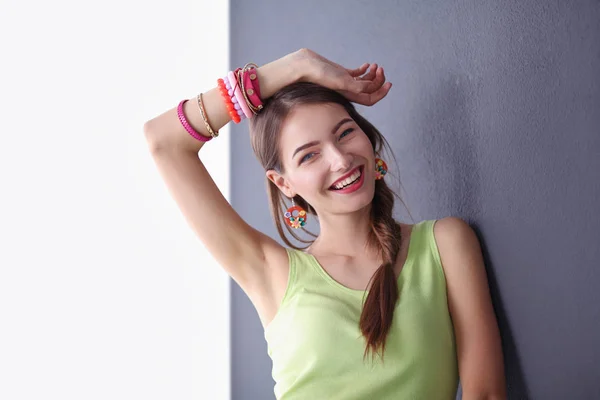 Portrait of a young smiling woman on a gray wall background — Stock Photo, Image