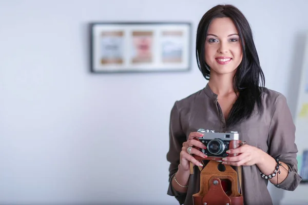 Portrait of smiling young woman with camera sitting in loft apartment — Stock Photo, Image