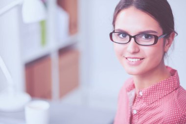 Güzel moda tasarımcısı stüdyoda masada oturuyor.