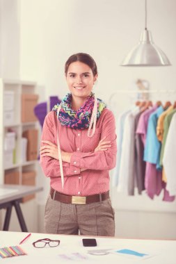 Güzel moda tasarımcısı stüdyoda masada oturuyor.