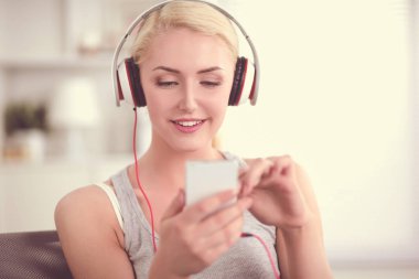 Evdeki genç ve güzel kadın kanepede oturup müzik dinliyor.