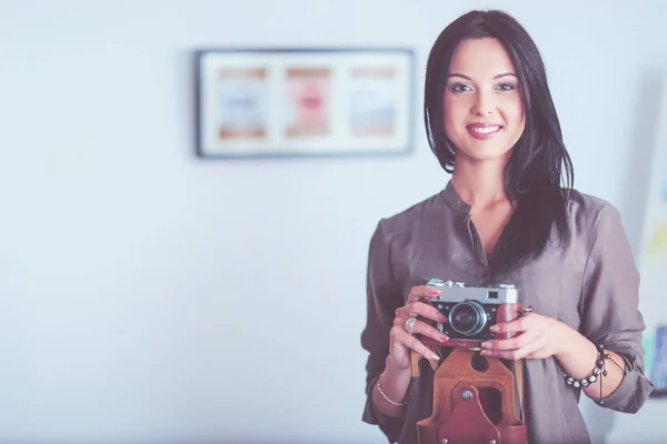 Portret van lachende jonge vrouw met camera zitten in loft appartement — Stockfoto