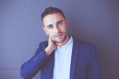 Gri arka planda yalnız oturan genç iş adamı.