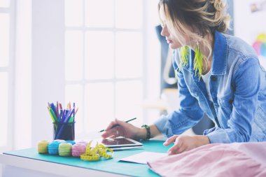 Moda tasarımcısı kadın stüdyoda tasarımları üzerinde çalışıyor.