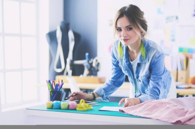 Moda tasarımcısı kadın stüdyoda tasarımları üzerinde çalışıyor.