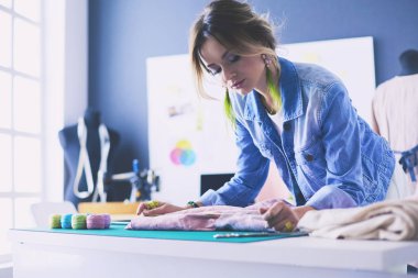 Moda tasarımcısı kadın stüdyoda tasarımları üzerinde çalışıyor.