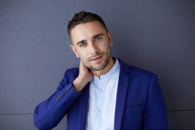 Gri arka planda yalnız oturan genç iş adamı.