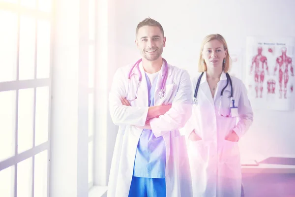 Schöner Arzt spricht mit junger Ärztin und macht sich Notizen, während er in seinem Büro sitzt. — Stockfoto