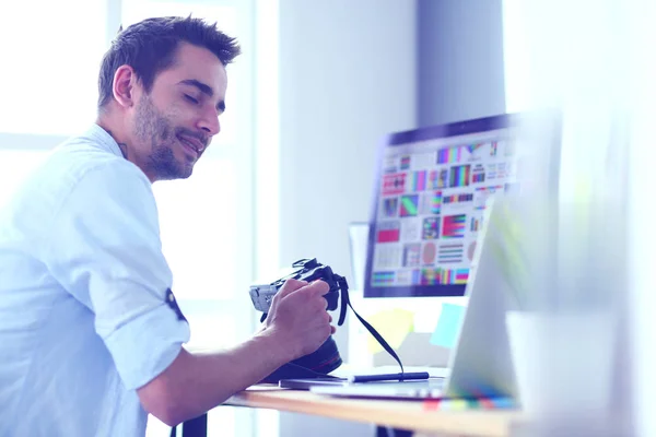 Портрет молодого дизайнера, сидящего в графической студии перед ноутбуком и компьютером во время работы в сети. — стоковое фото