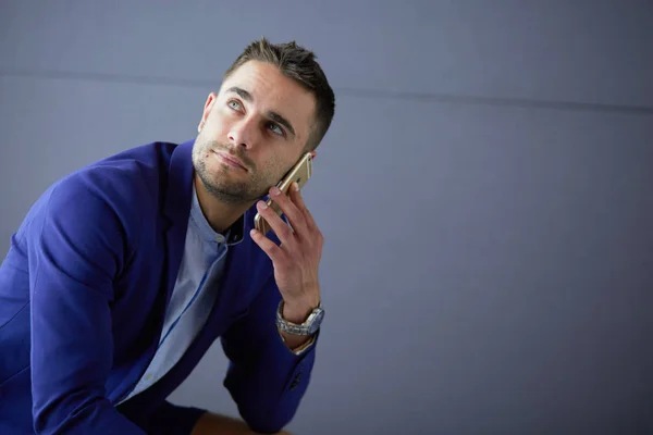 Joven empresario sentado aislado sobre fondo gris. —  Fotos de Stock