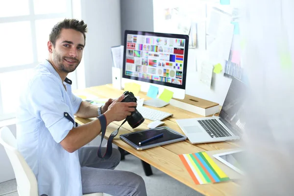 Porträt eines jungen Designers, der im Grafikstudio vor Laptop und Computer sitzt, während er online arbeitet. — Stockfoto