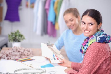Güzel moda tasarımcısı stüdyoda masada oturuyor.