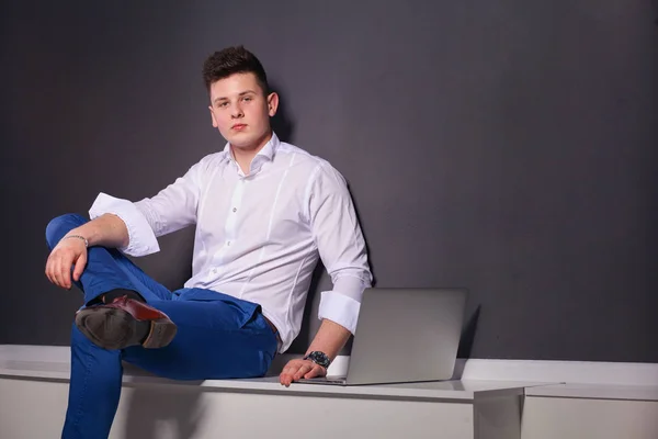 Handsome young man with laptop on black background — Stock Photo, Image