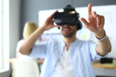 Genç erkek yazılım programcısı ofiste üç boyutlu sanal gerçeklik gözlükleriyle yeni bir uygulama test ediyor..