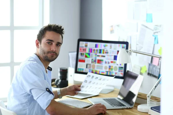 Porträt eines jungen Designers, der im Grafikstudio vor Laptop und Computer sitzt, während er online arbeitet. — Stockfoto