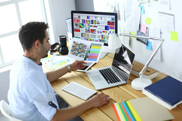 Porträt eines jungen Designers, der im Grafikstudio vor Laptop und Computer sitzt, während er online arbeitet. — Stockfoto