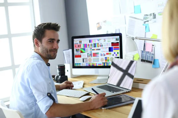 Porträt eines jungen Designers, der im Grafikstudio vor Laptop und Computer sitzt, während er online arbeitet. — Stockfoto