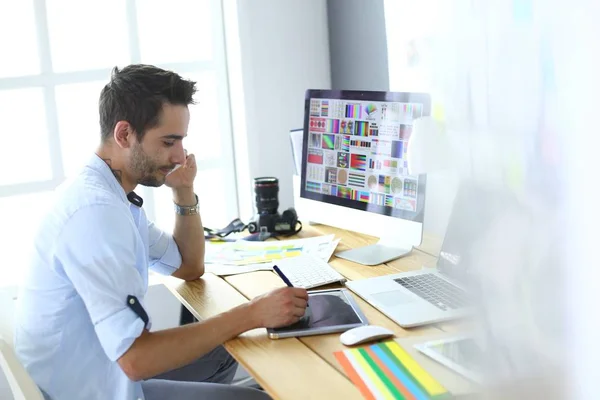 Portrait de jeune designer assis dans un studio graphique devant un ordinateur portable et un ordinateur tout en travaillant en ligne. — Photo