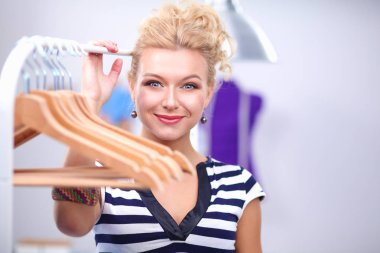 Raf ofiste askıları ile yakınındaki güzel genç stilist