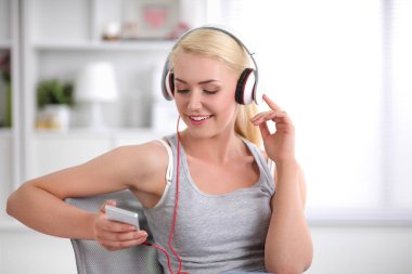 Evdeki genç ve güzel kadın kanepede oturup müzik dinliyor.