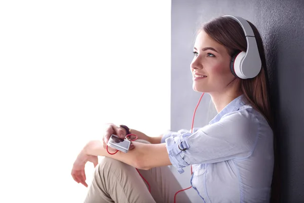 Gadis muda yang bahagia duduk di lantai dan mendengarkan musik — Stok Foto