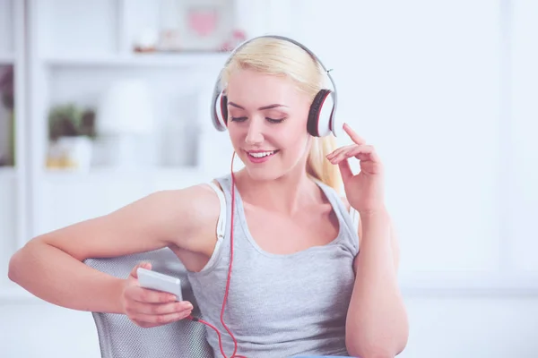 Jonge mooie vrouw thuis zitten op de bank en luisteren muziek — Stockfoto