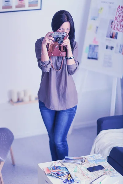 Porträtt av leende ung kvinna med kameran sitter i loftlägenhet — Stockfoto