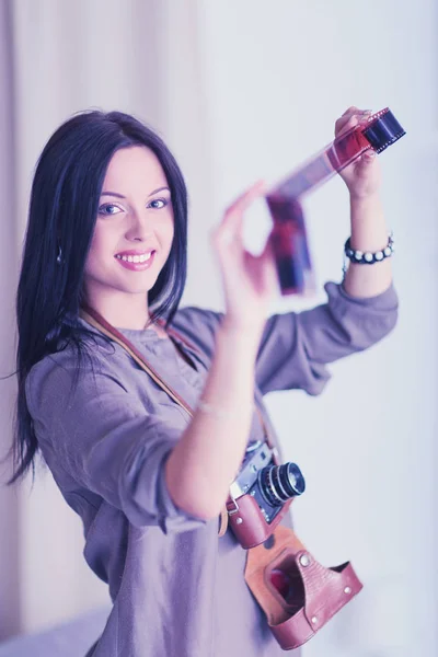 Portret van lachende jonge vrouw met camera zitten in loft appartement — Stockfoto