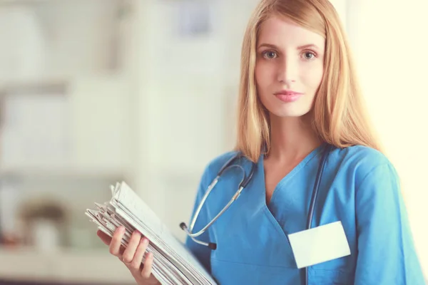 Retrato de doctora con estetoscopio en el pasillo del hospital, sosteniendo una carpeta. — Foto de Stock