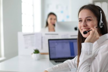 Ofisinde kulaklık ve bilgisayarla gülümseyen iş kadını ya da yardım hattı operatörü