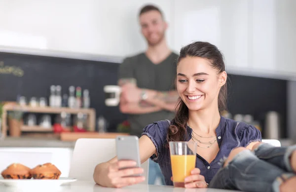 Lyckliga par med smartphone som sitter i köket — Stockfoto