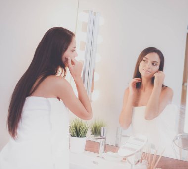 Çekici genç bir kadın yüzüne krem sürüyor.