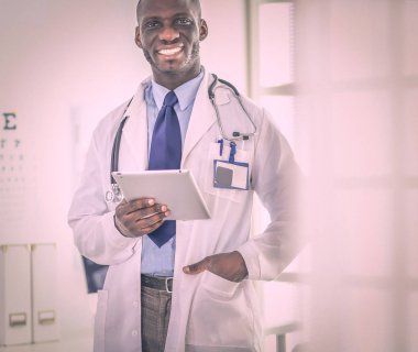 Tablet bilgisayarlı siyahi bir doktor hastanede bekliyor.