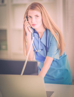 Kadın doktor teşhis merkezinde telefonla konuşuyor.