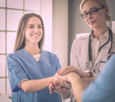 Doktorlar ve hemşireler tıbbi bir ekipte el ele tutuşuyorlar.