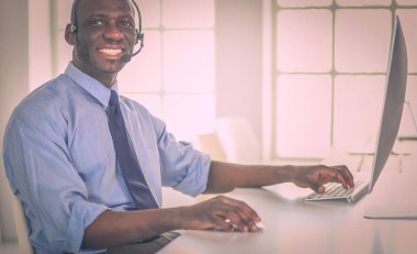 Kulaklıklı Afro-Amerikan işadamı laptopuyla çalışıyor.