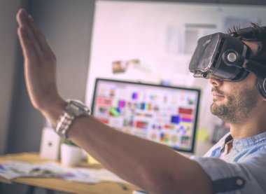 Genç erkek yazılım programcısı ofiste üç boyutlu sanal gerçeklik gözlükleriyle yeni bir uygulama test ediyor..