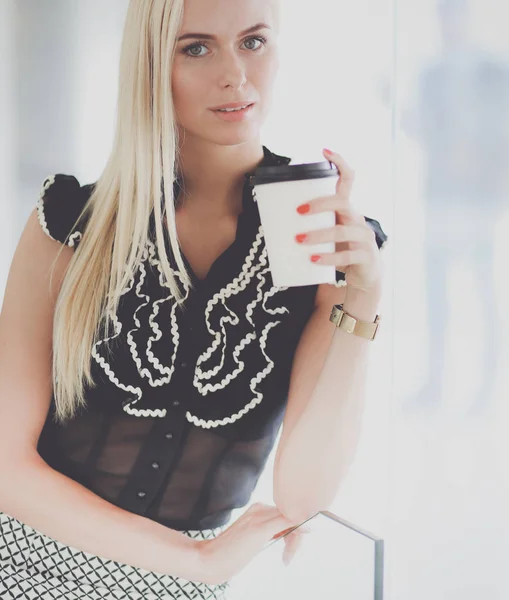 Empresaria sosteniendo una taza de café de pie en la oficina  . — Foto de Stock