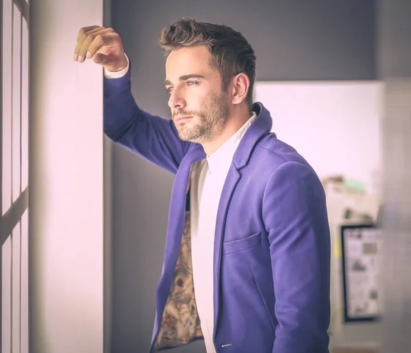 Hombre de negocios en traje hablando por teléfono y mirando hacia otro lado cerca de la ventana . — Foto de Stock