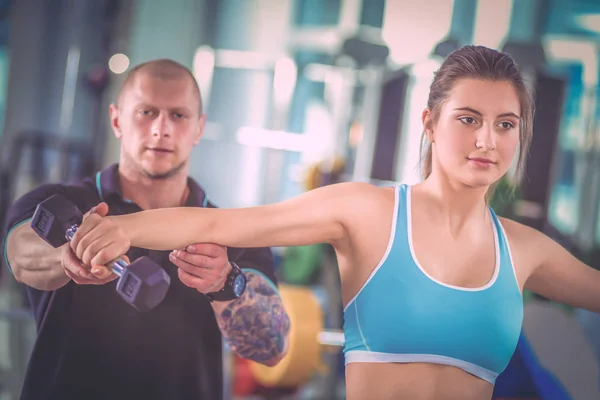 Beautiful woman at the gym exercising with her trainer. Beautiful woman. Gym