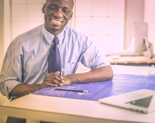 Afrikaans-Amerikaanse architect werkt met computer en blauwdrukken in kantoor — Stockfoto