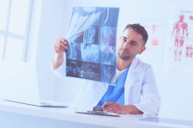 Yakışıklı doktor genç bayan hastasıyla konuşuyor ve ofisinde otururken notlar alıyor..