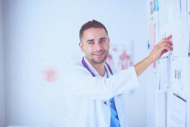 Genç ve kendinden emin erkek doktor portresi tıp ofisinde duruyor..