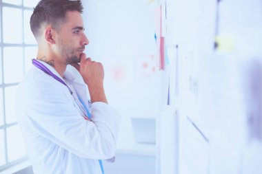 Genç ve kendinden emin erkek doktor portresi tıp ofisinde duruyor..